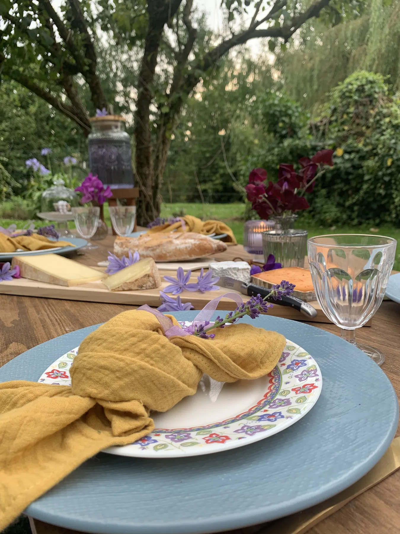 Table de jardin, serviettes moutarde et vaisselle fleurie